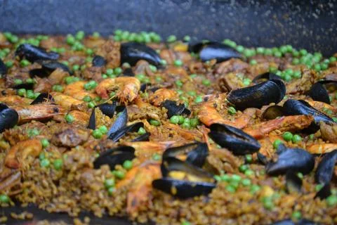 A large shallow pan overflows with steaming traditional spanish paella loaded Stock Photos