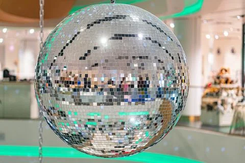 A large, shiny disco ball is the central focus in a white interior space Made Stock Photos