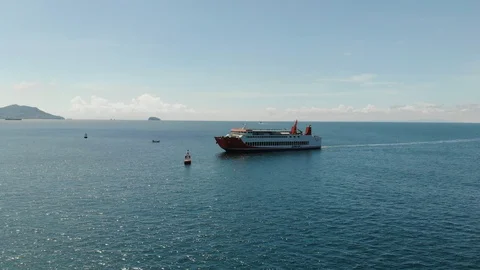 A large ship arriving from the open ocean enters a pier on a sunny day overlooki Stock Footage