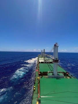 A large ship cuts through the waves under a blue clear sky on the open sea Photos