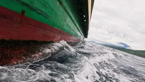 Large ship sails through turbulent ocean waters on a cloudy day near coastline. Video stock 328047192