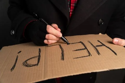 Large shot of writing text asking for help on cardboard. The concept of begging Stock Photos