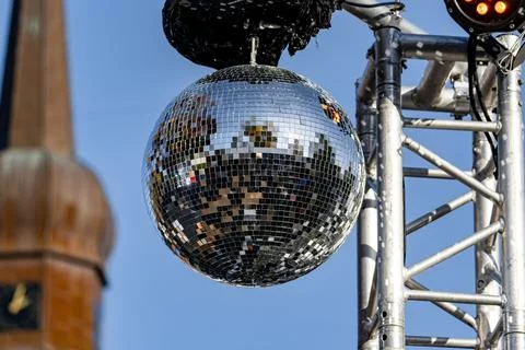 A large silver ball with a mirror on it is suspended from a metal structure Stock Photos