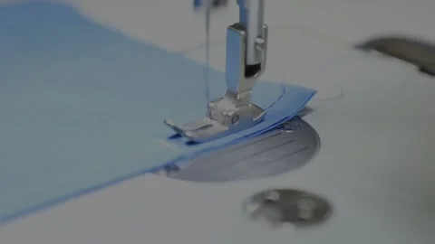 Large silver needle of sewing machine works on blue fabric Stock Footage 136400533