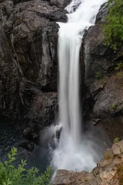 A large single drop waterfall cascading into the river below Stock Photos