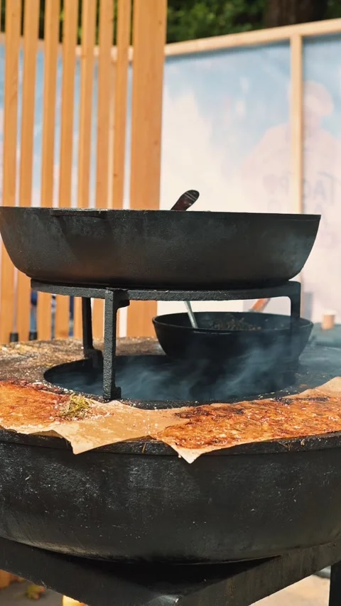 The large skillet is positioned over an open flame, cooking food. The setting Stock Footage 345886629
