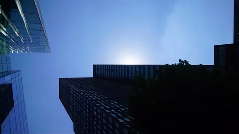 Large skyscrapers loom over head as sun bursts out from behind Stock Footage 110983533