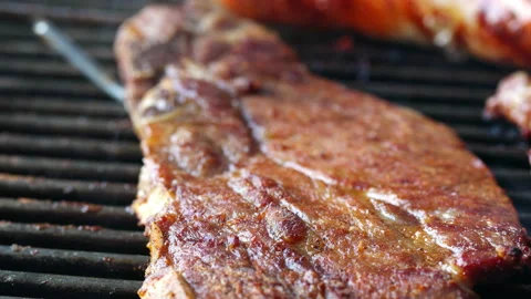 A large slice of pork lies on a grill and roasts. Then it is turned over. You Stock Footage 163050863