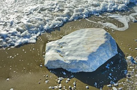 A large smooth block of white marble in the sand on the coast Stock Photos
