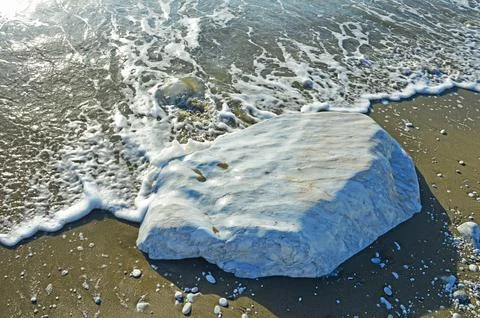 A large smooth block of white marble in the sand on the coast Foto stock