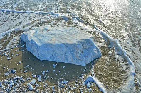 A large smooth block of white marble in the sand on the coast Stock Photos