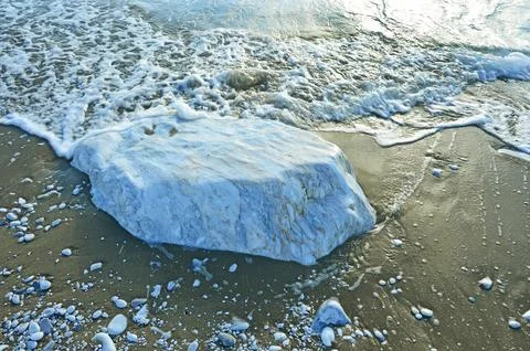 A large smooth block of white marble in the sand on the coast Stock Photos