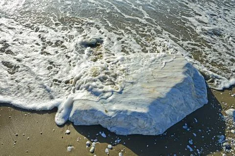 A large smooth block of white marble in the sand on the coast. Selective focu Foto stock
