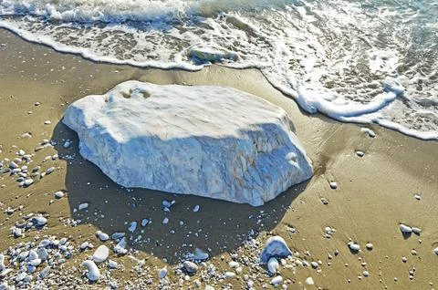 A large smooth block of white marble in the sand on the coast. Selective focu Stock Photos