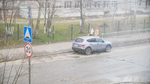 Large snow flakes falling down during an early spring on city street with green Stock-Footage 129670713