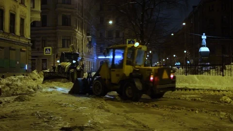 Large snow tractor clearing snow from the street at night. Snow plow outdoors Stock Footage 107650814
