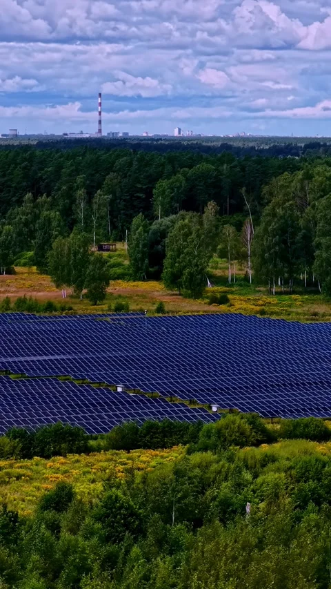 A large solar array in the foreground with natural landscape and an industrial Stock Footage 321056644