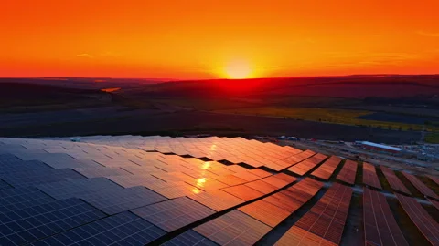 Large solar array reflecting orange dusk across open farmland. Close overhead Stock Footage 336387029