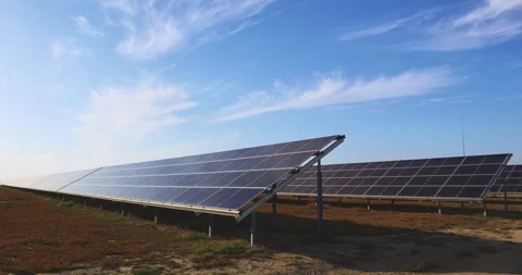 Large solar array stretching across open field under wispy blue sky outdoors Stock Footage 336396727