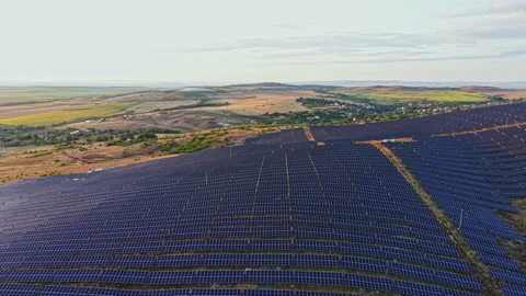Large solar farm sits on a hill with rows of solar panels stretching across the Stock Footage 340932914