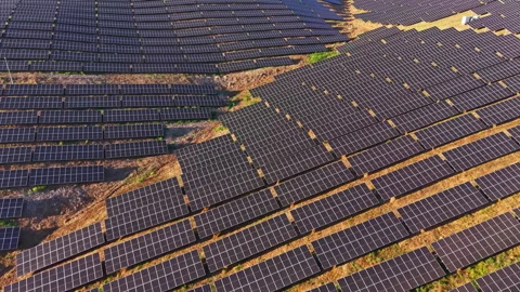 Large solar panel array covering a field in a rural area during the day under Видео 344777407
