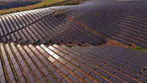 Large solar panel array covers a hillside in a rural area during daytime with Видео 344778775