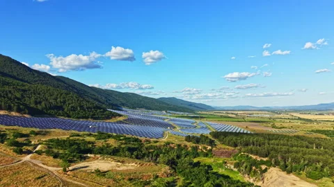 Large solar panel array is installed in a rural area surrounded by mountains and Stock Footage 339519281