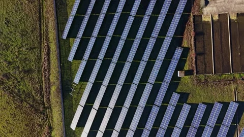 Large solar panel array in wide open field near industrial site Stock Footage 334027930