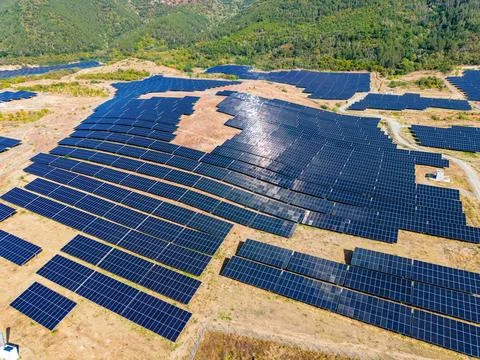 Large solar panel arrays cover a hillside area, capturing sunlight for energy Stock Photos