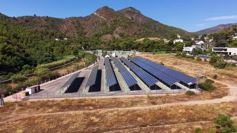 Large solar panel carport array in a parking lot surrounded by dry hills and Vídeo Stock 345103881