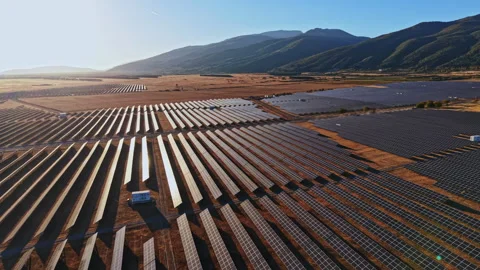 Large solar panel farm located in a valley with mountains in the background Stock Footage 347763563