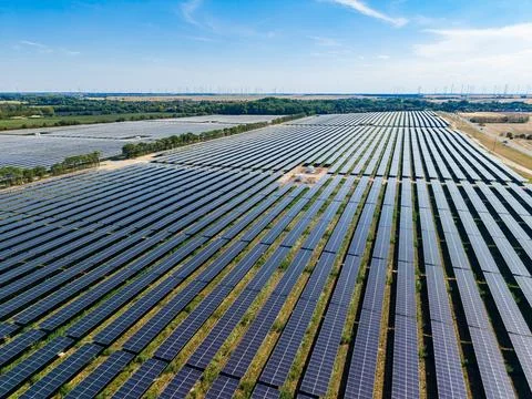 Large solar panel farm located in a flat area with rows of solar panels str.. Stock Photos