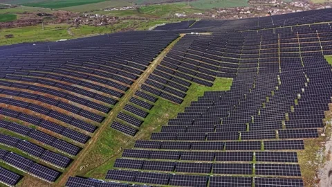 Large solar panel field in rural area with green landscape nearby Vidéo 337940601