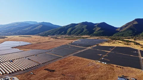 Large solar panel installation on flat land in a valley surrounded by mountains Stock Footage 347761768