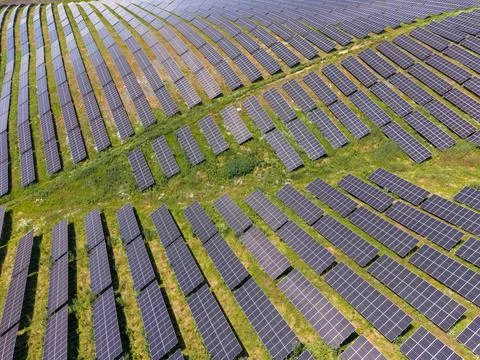 Large solar panel installation in a green field during daytime Stock Photos