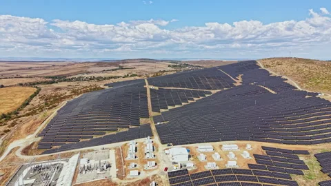Large solar panel installation on an open landscape with hills and clouds in the Stock Footage 346980106