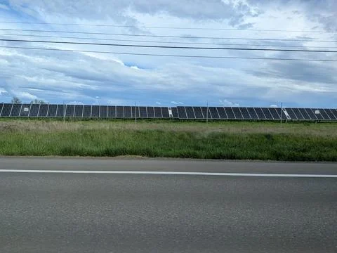 Large solar panel installation stretches behind a fenced perimeter Fotos de archivo