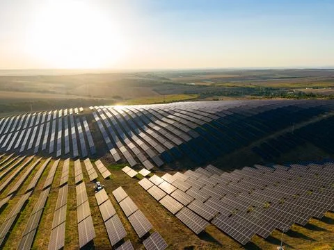 Large solar panel installation stretches across a field at sunset. Sunlight r Stock-Fotos