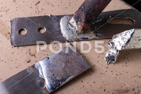 A large soldering iron and soldering accessories on a workshop table. Connect Stock Photos