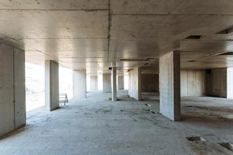 A large, spacious empty room featuring unfinished concrete walls and sturdy.. Stock Photos