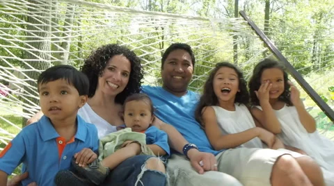 Large Spanish family sitting in hammock together Stock Footage
