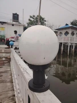 Large spherical navigation light mounted on wooden bridge near waterway wit.. Fotos Stock