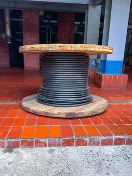 A large spool of wire is currently resting on a tiled floor Foto stock