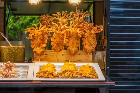 Large squids coated in battered and fried on  skewers for sale on a food truck. Stock Photos