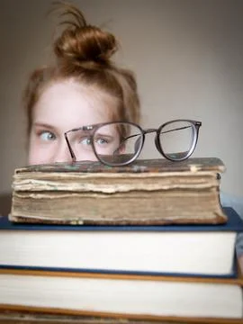A large stack of books with glasses on top. From behind the stacks through the Stock Photos