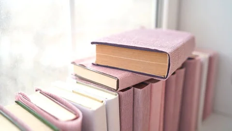 Large stack of books on windowsill. Books wrapped in colored paper lie on window Stock Footage 126530253