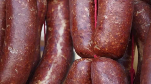 A large stack of deli sausages is on display at a market for sale, tied with Stock Footage 277377319