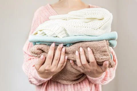 Large stack of folded knitted sweaters in warm pastel colors Foto stock
