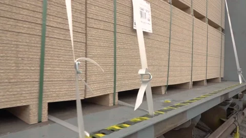 A large stack of full size OSB chipboard on a pallet strapped Vidéo 169602739
