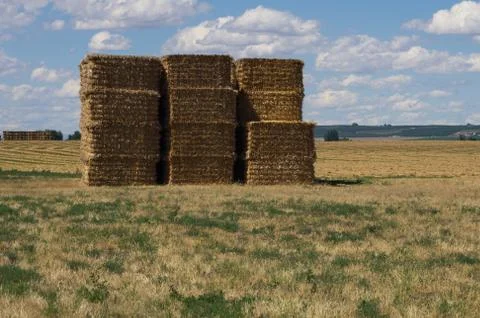 Large stack of hay bales under cloud studded sky Stock Photos